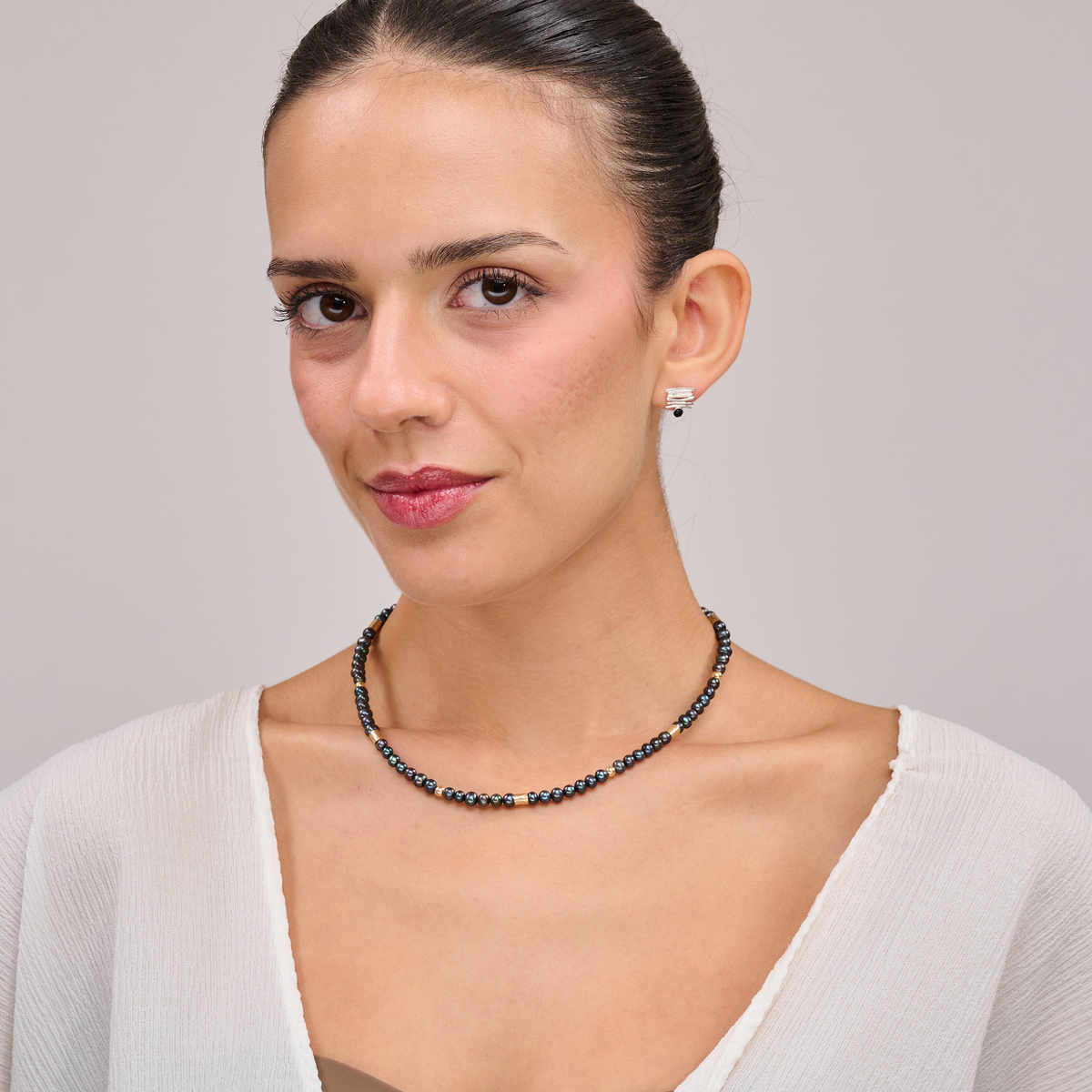 שרשרת צמודה עם פנינים שחורות ואלמנטים מוזהבים – קולר עם אמירה מסוגננת, שמשלב בין עומק אלגנטי לנגיעה חמימה של זהב. הפנינים השחורות יוצרות נוכחות דרמטית אך הרמונית, ואילו חרוזי הגולדפילד מוסיפים קונטרסט זוהר וקו עיצובי נקי אך מרשים. העיצוב הצמוד לצוואר מדגיש את קווי המתאר ומעניק מראה נשי, חזק ומתוחכם. תכשיט פריט ורסטילי שמשדר יוקרה ורוך.